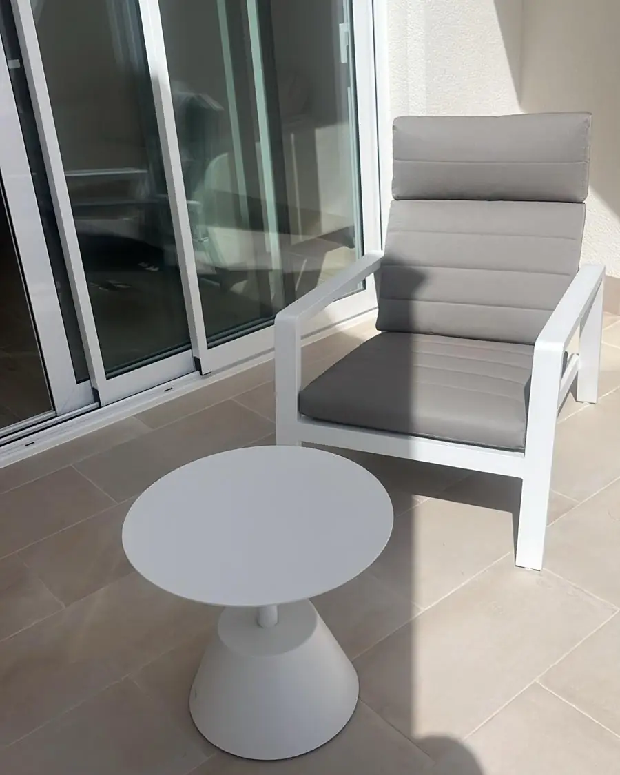 Een fauteuil en een bijzettafel op het balkon, naast de schuifpui